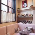 Pink banquette seating and natural wine shelves inside Stem, one of the best restaurants in Brighton and Hove