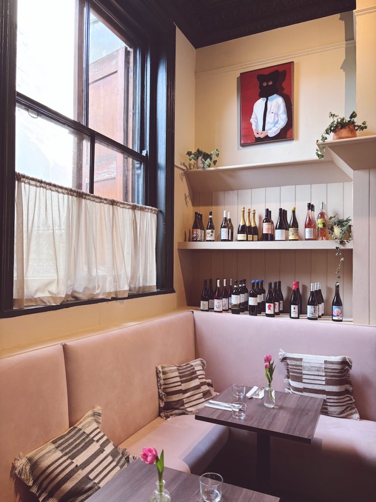 Pink banquette seating and natural wine shelves inside Stem, one of the best restaurants in Brighton and Hove