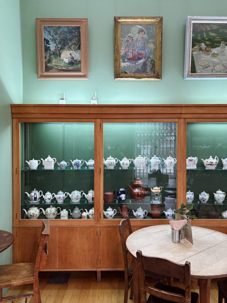 Café Rust at Hove Museum, antique teapot display cabinets in a green-walled room