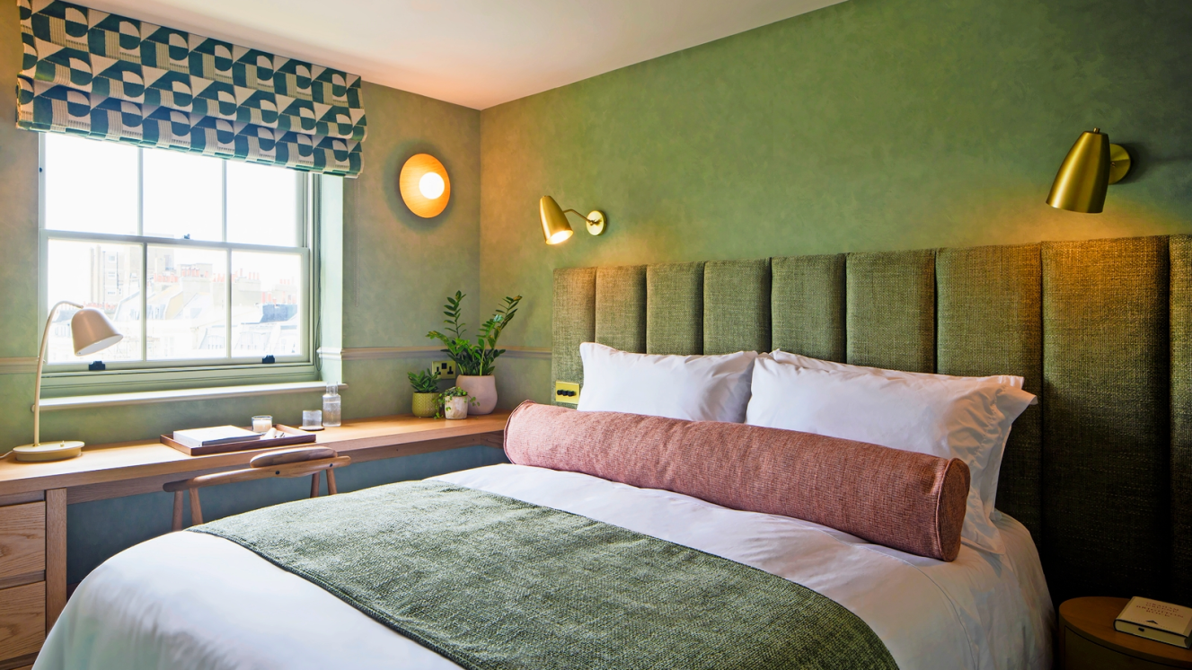 Green bedroom at Regency Square Suites Brighton with upholstered headboard and patterned Roman blind