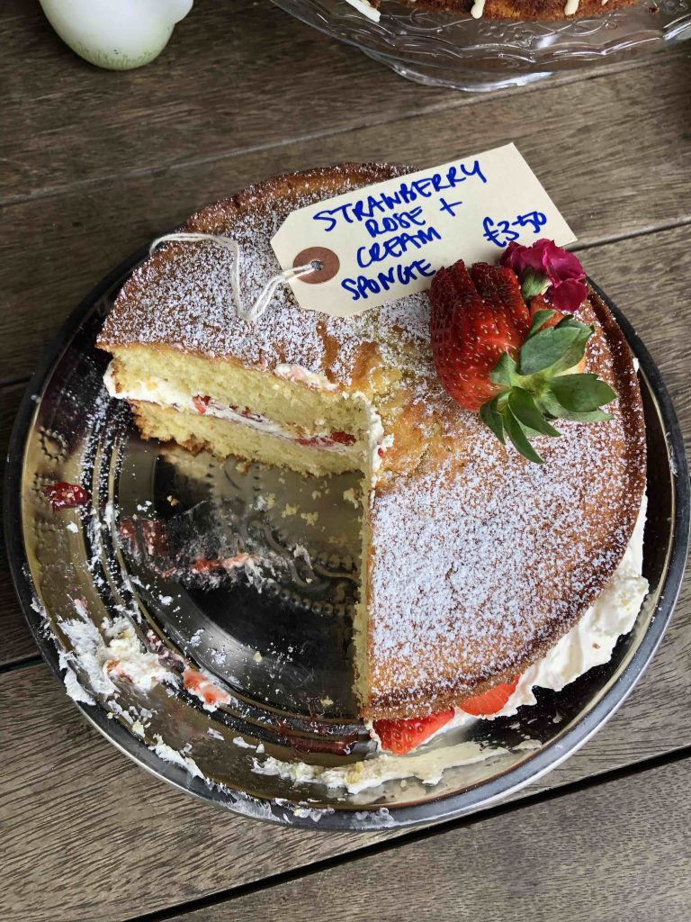 a victoria sponge cake decorated with strawberries on a glass cake stand 