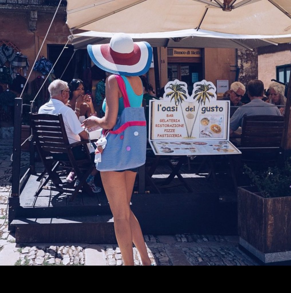 picture of a lady in shorts and a straw hat buying gelato in Italy