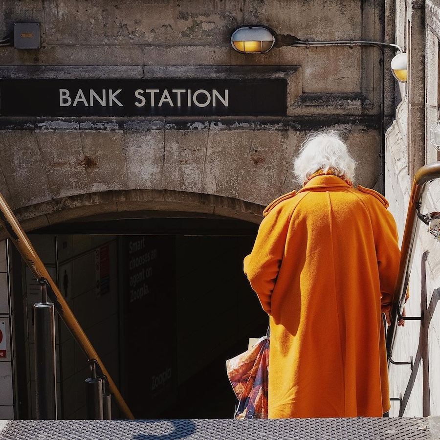 picture of a lady with white hair in an orange coat at Bank Underground station