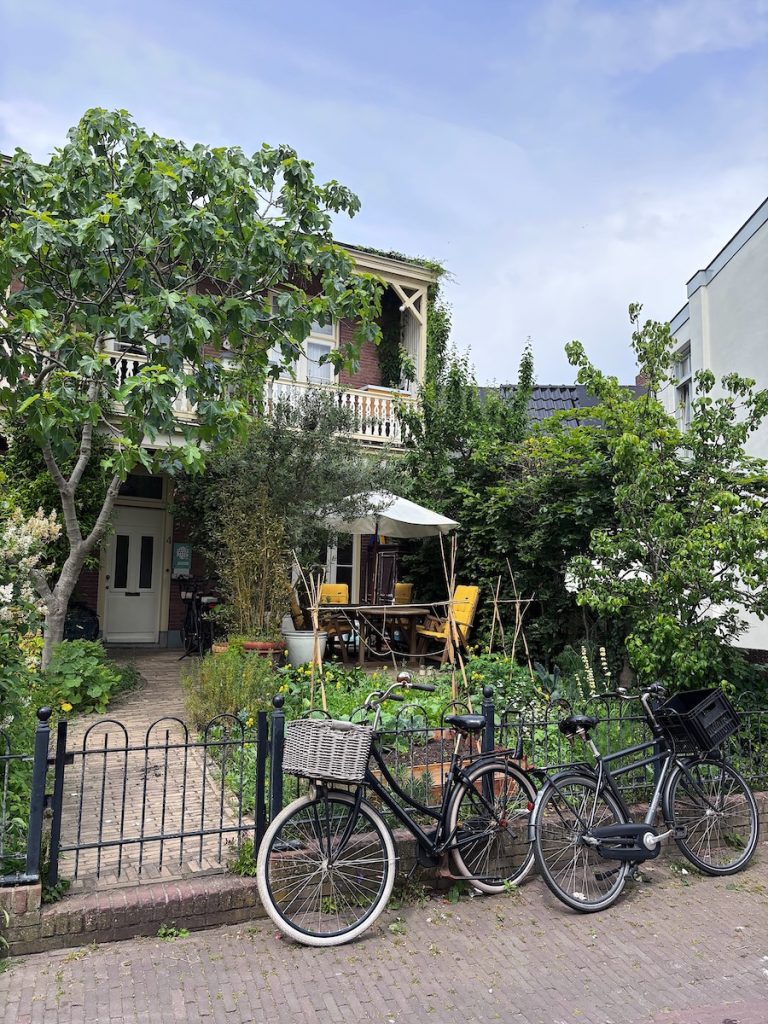 Two Dutch bicycles parked outside a brick townhouse with an overgrown front garden and balcony, Zandvoort, North Holland