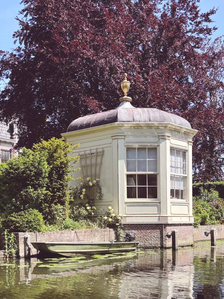 Elegant octagonal summerhouse with copper dome and gold finial sitting over a lily pad canal, Edam, North Holland