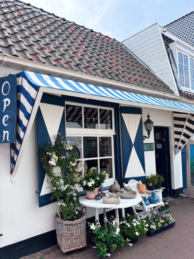 Charming blue and white striped shopfront with ceramic bird sculptures, white flowers and a wicker basket outside a gift shop in the Sloppies, Zandvoort, North Holland