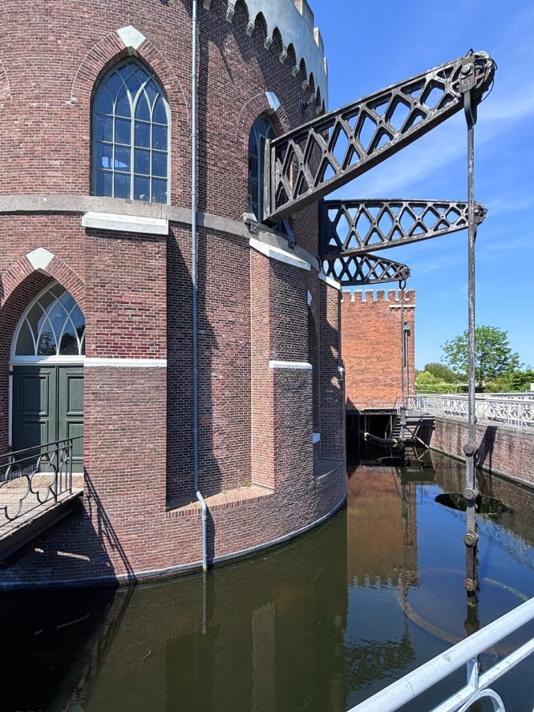 Gothic red brick Cruquius pumping station with arched windows and giant iron sluice mechanism over water, Haarlemmermeer, North Holland