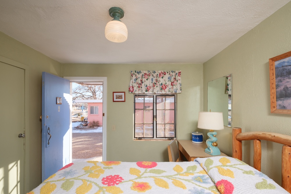 Guest room at the Blue Swallow Motel in Tucumcari, New Mexico, with floral chenille bedspreads and pale green walls