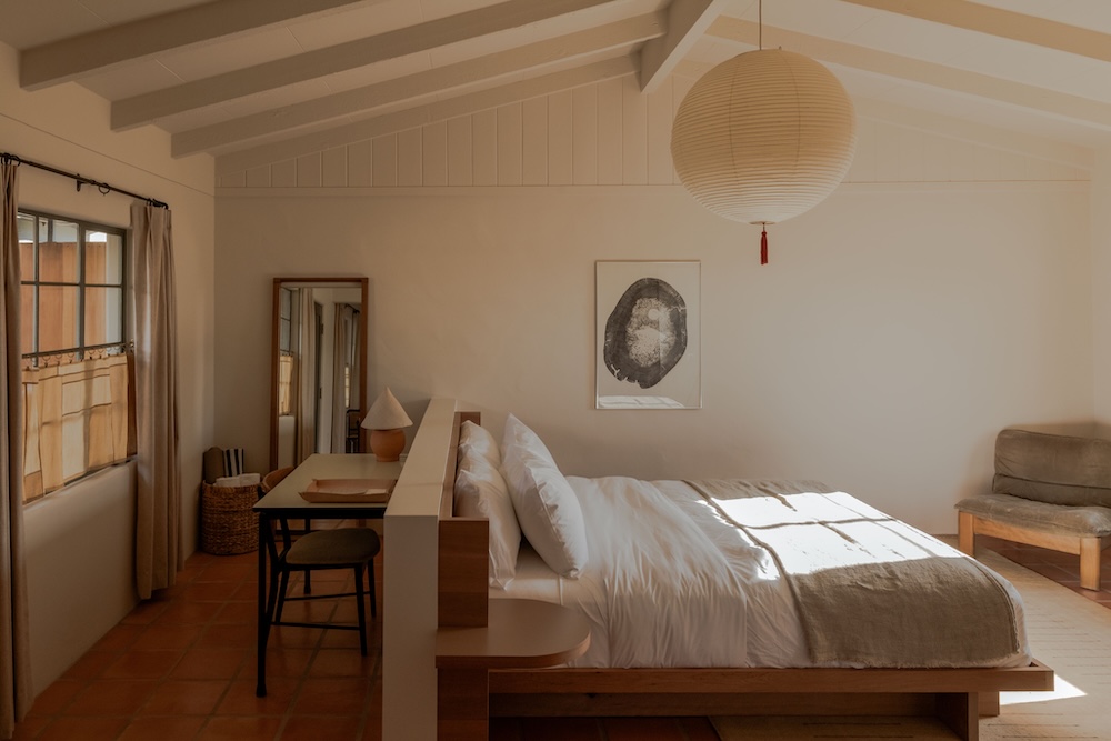 Minimalist guest room at Hotel Wren in Twentynine Palms with timber bed, terracotta floor and paper lantern