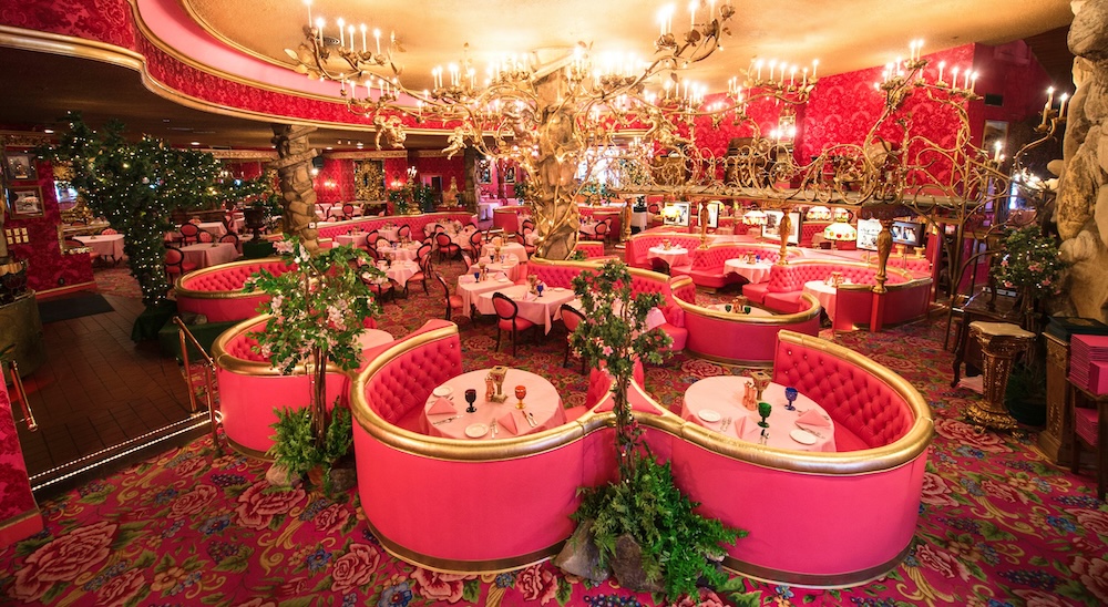 Pink dining room at the Madonna Inn in San Luis Obispo with ornate chandeliers and curved booths