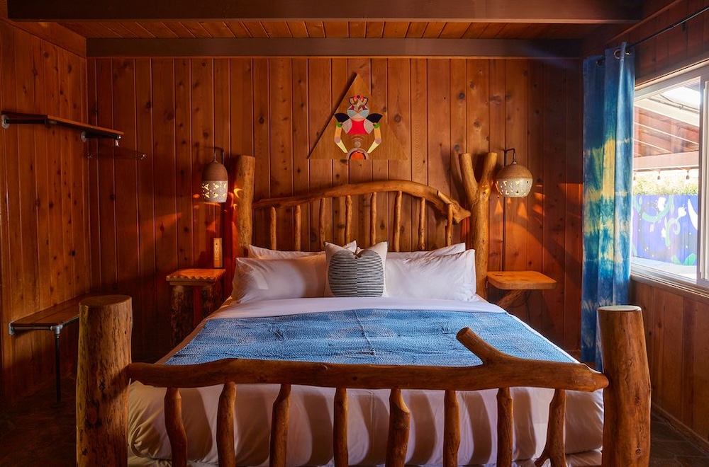 Wood-panelled guest room at Ojai Rancho Inn with a rustic log bed and blue textiles