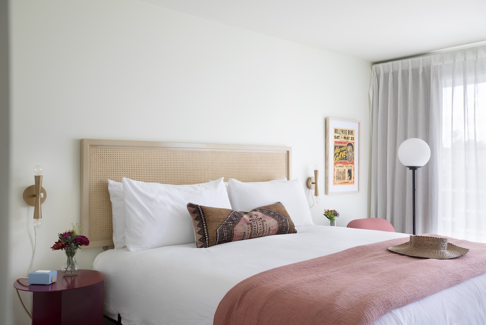 Guest room at Starlight Motor Inn with cane headboard, pink accents and vintage artwork