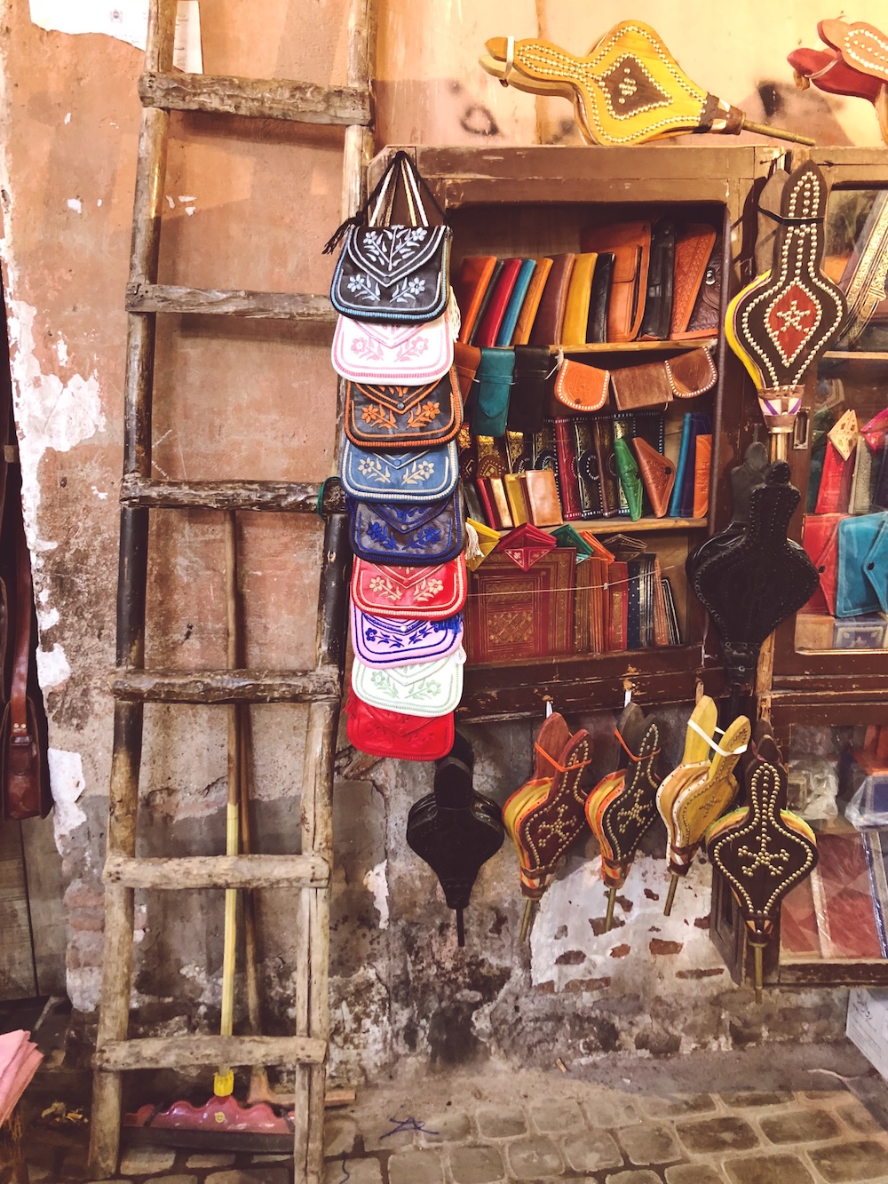 Embroidered leather bags, wallets and studded bellows hanging in a souk stall in Marrakech